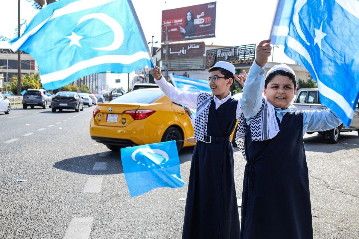 أطفال يلوحون بأعلام التركمان العراقيين في مدينة كركوك. (أ ف ب)