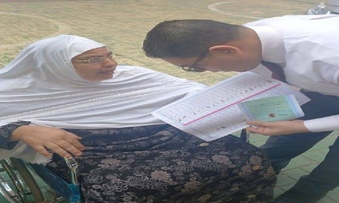 قاضٍ يساعد سيدة مسنّة على الإدلاء بصوتها داخل لجنة بإيتاي البارود قاضٍ يساعد سيدة مسنّة على الإدلاء بصوتها داخل لجنة بإيتاي البارود